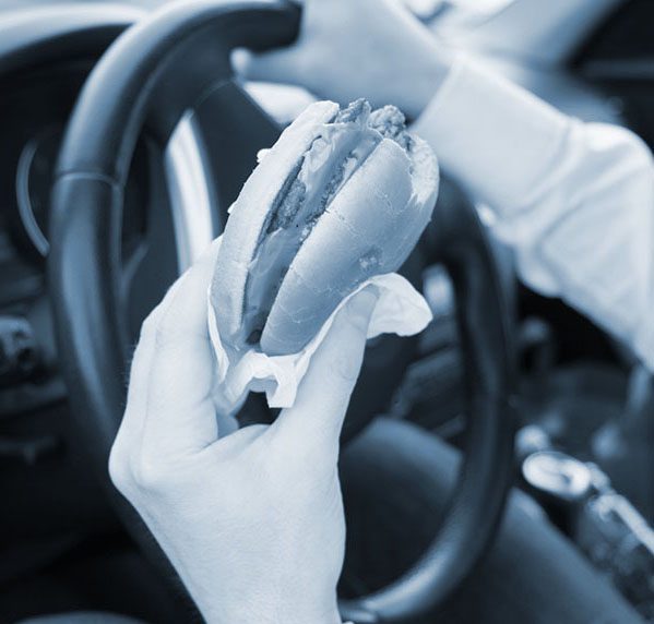 Man eating an hamburger while driving his car