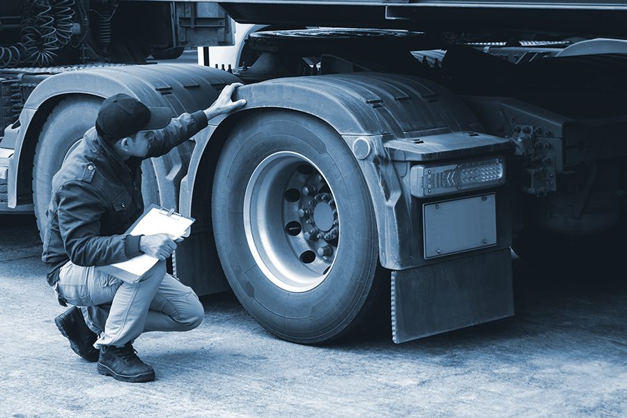 Truck driver inspecting safety check a truck tires