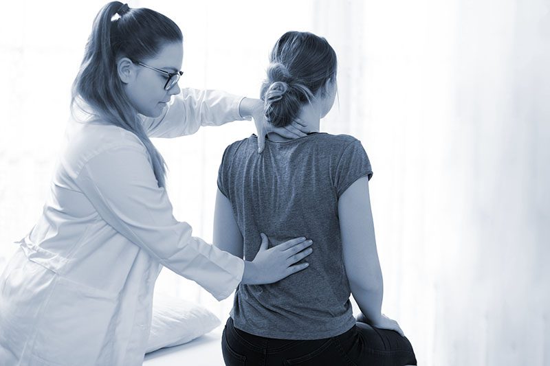 Female physiotherapist or a chiropractor examining patients back.