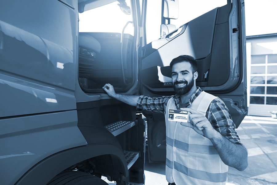 Truck driver candidate showing CDL driving license. Successfully passed training driving exam.