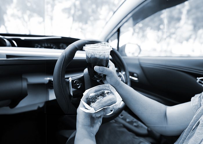 woman driver hold and eat hamburger in car, dangerous and risk an accident.