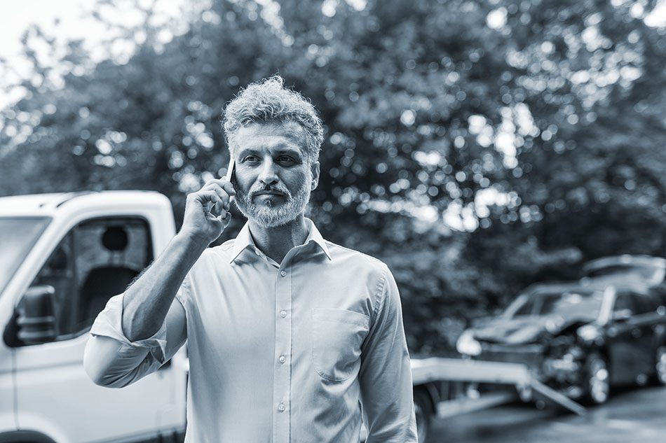 Mature man making a phone call after a car accident.