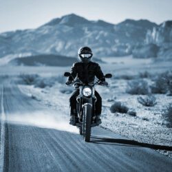 A man rides his motorcycle down a dirt road in the desert